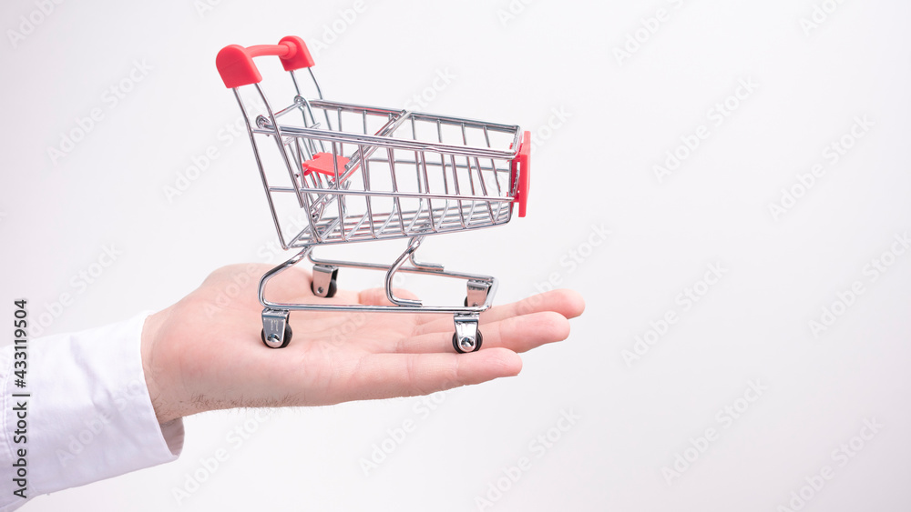 Man shows a shopping cart on a white background, side view, copy space, 16:9 Man shows a shopping cart on a white background, side view, copy space, 16:9