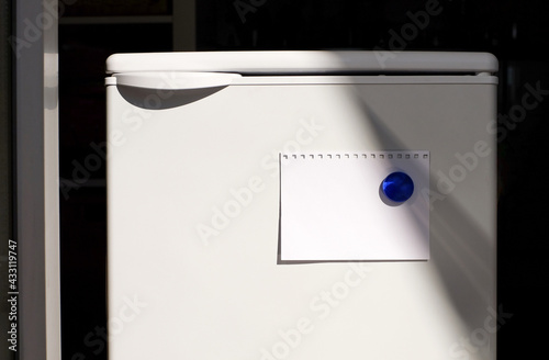 Note paper on fridge with glass magnet, sunlight, copy space