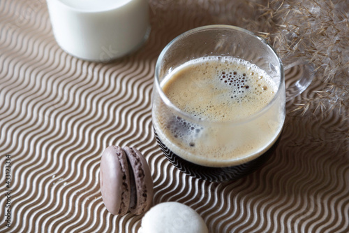 Hot cup of black coffee with macarons and milk. Close up glass . 