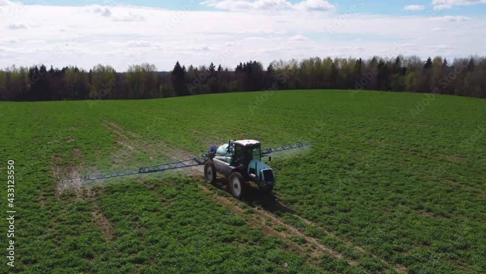 Aerial view of farming tractor spraying mineral, nitrogen fertilizer or pesticides on an green agricultural field. Aerial view of farming tractor spraying mineral, nitrogen fertilizer or pesticides on an green agricultural field.