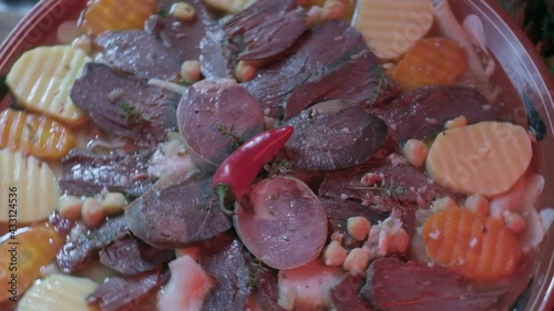 Close-up of national Kazakh dish Beshbarmak made of veggies, dough and horsemeat served in deep clay dish with hot red pepper on top photo