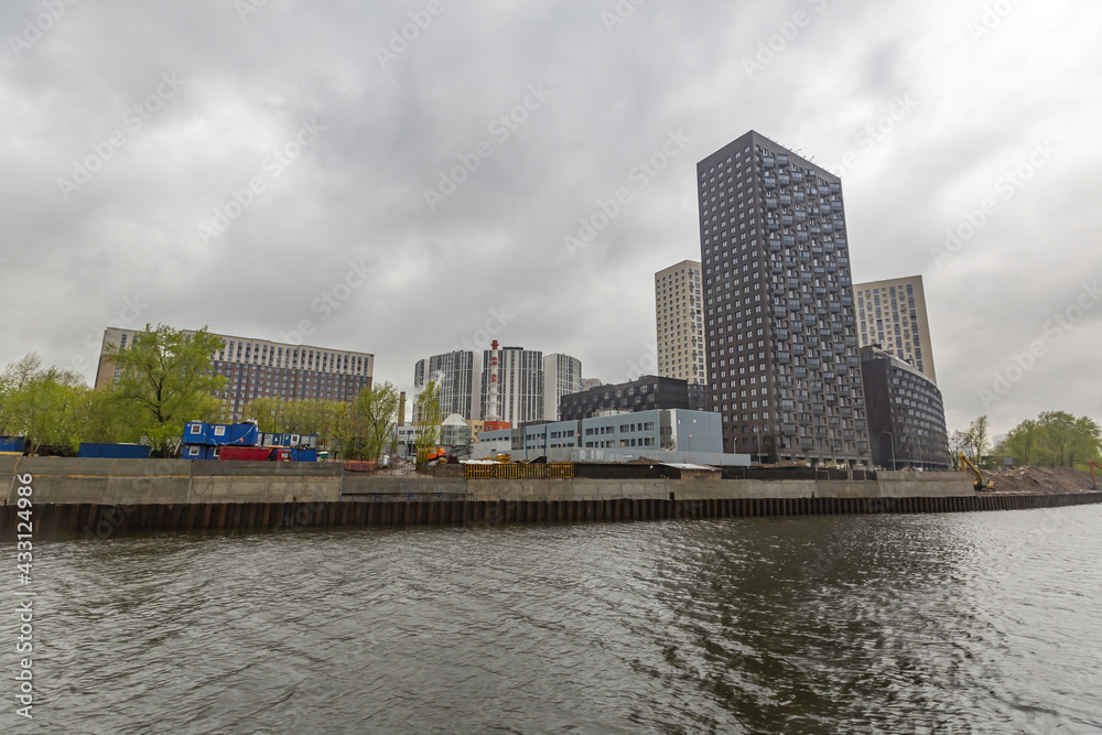 Residential buildings on the banks of Moskva River on a cloudy day. Housing construction according to the city renovation program. Moscow, Russia