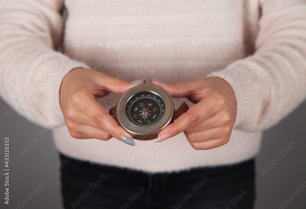 Compass in the hand of a young woman. Gray background. Compass in the hand of a young woman. Gray background.