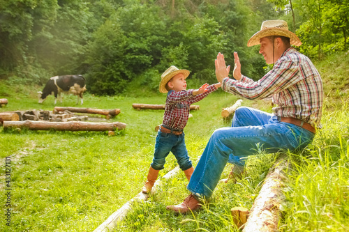 happy child with cowboy parent in nature in the field