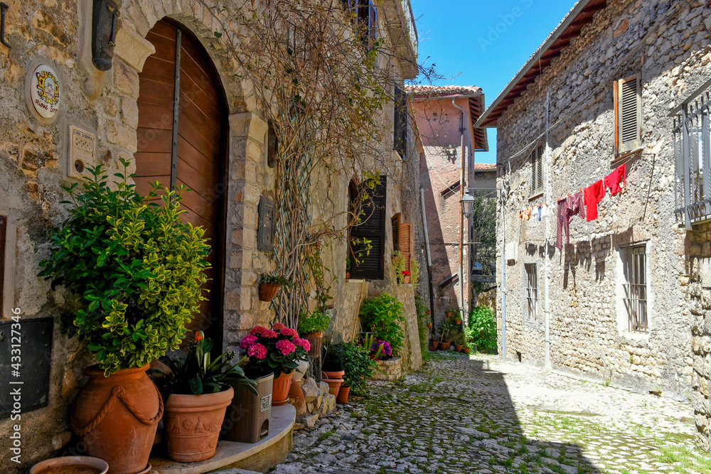 Fototapeta premium Sermoneta, Italy, 05/10/2021. A street between old medieval stone buildings in the historic town.