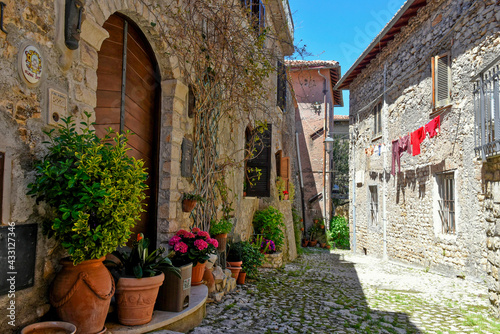Fototapeta Naklejka Na Ścianę i Meble -  Sermoneta, Italy, 05/10/2021. A street between old medieval stone buildings in the historic town.