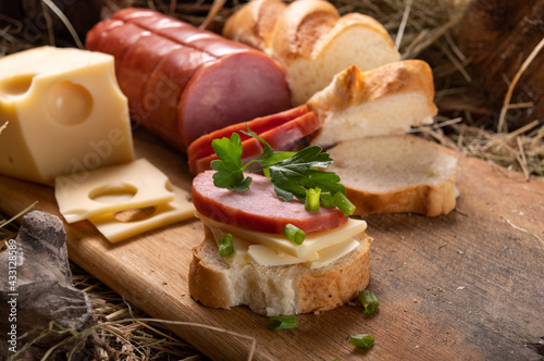 Sausage baguette sandwich. Close-up sandwich. The products lie in the hay.