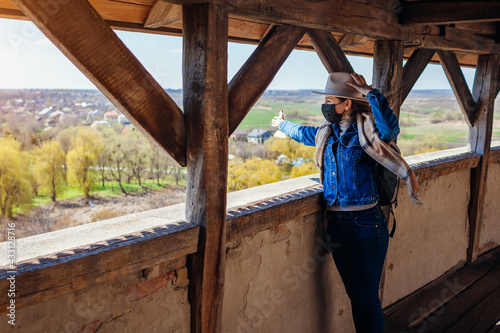 Tourist walking on Olesko Castle balcony admiring spring landscape wearing mask during coronavirus covid-19 pandemic.