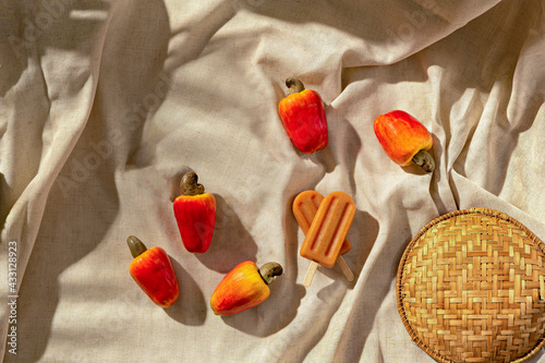 Cashew Popsicle with cachew fruits on a fabric base, sunlight, top view