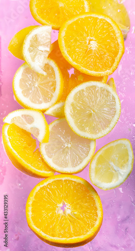 Fresh oranged and lemons on a pink background.