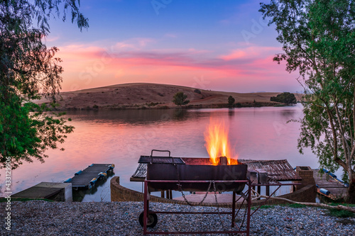 Sunset view of a still, silent dam with camp fire in the foreground,  Club Elani Resort, Cape Town, South Africa photo