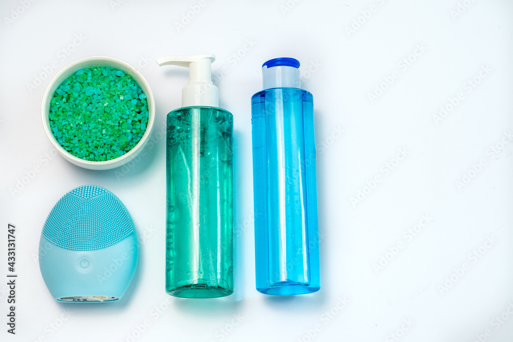 Cosmetic flat lay: health care products, bath salt and facial massager in green and blue colours on a white background. Natural organic product, beauty and spa concept Cosmetic flat lay: health care products, bath salt and facial massager in green and blue colours on a white background. Natural organic product, beauty and spa concept
