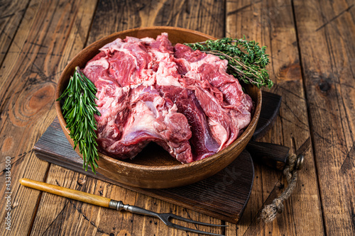 Boneless raw mutton Lamb Shoulder meat in wooden plate with herbs. wooden background. Top view