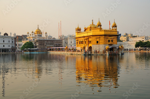 The sacred Golden Temple in the warm evening sun reflected in the water of the surrounding lake in Amristar, India photo