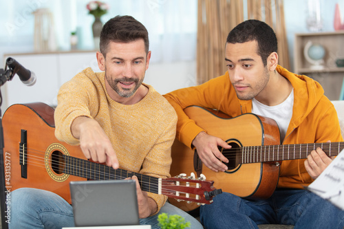 young man learning to play the guitar with teacher