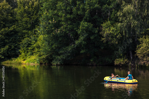 Children boys having a river adventure trip on boat during summer holidays in countryside concept for happy childhood