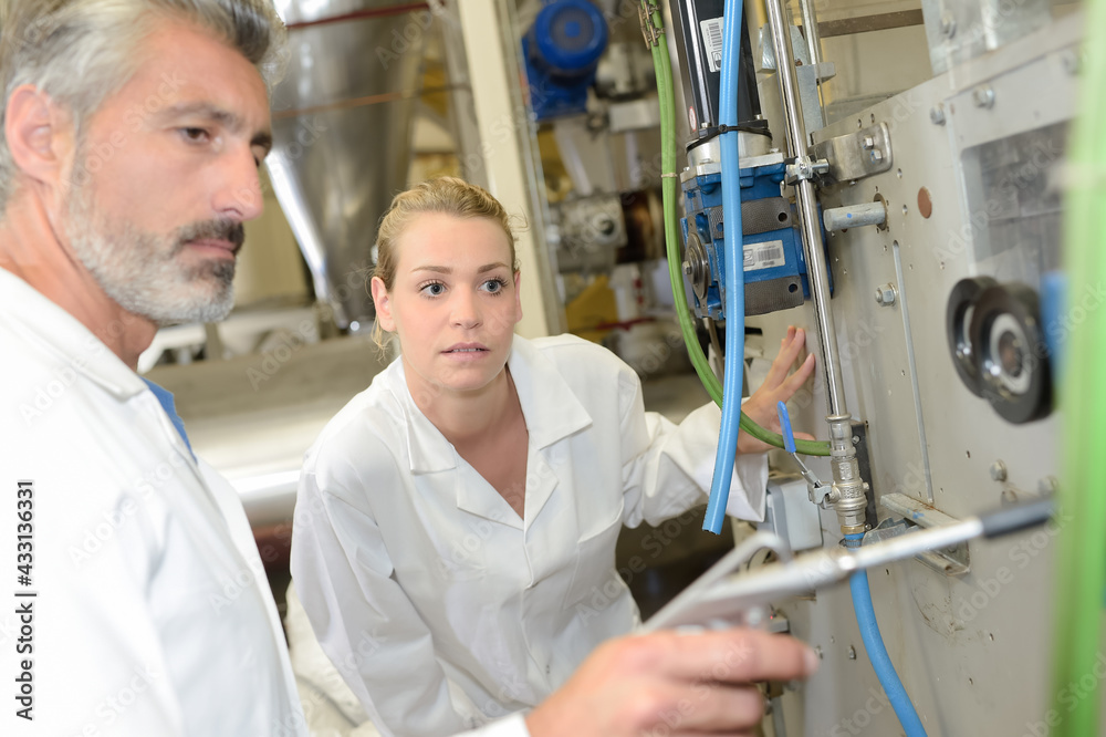 Obraz premium Man adjusting machine, lady looking on