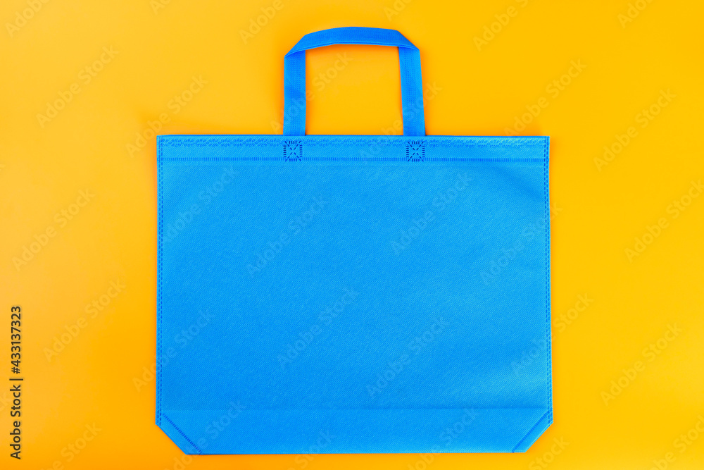 The blue shopping bag on a yellow background. Mockup for design. Shopping and sale concept