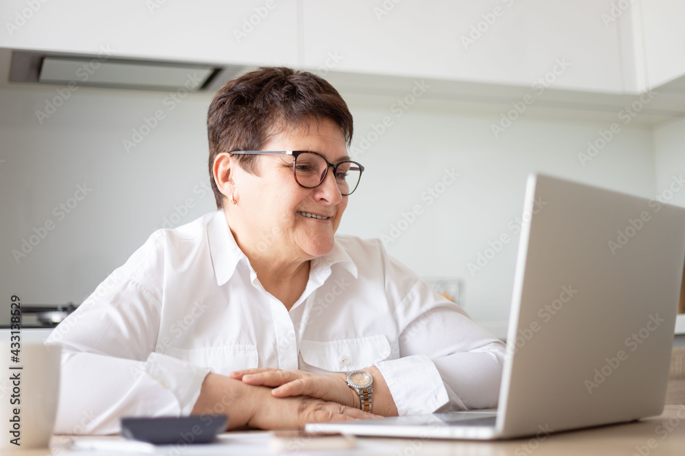 Smiling mature middle aged business woman using laptop working on computer,distance learning from home office, conference calling in virtual chat meeting. Smiling mature middle aged business woman using laptop working on computer,distance learning from home office, conference calling in virtual chat meeting.
