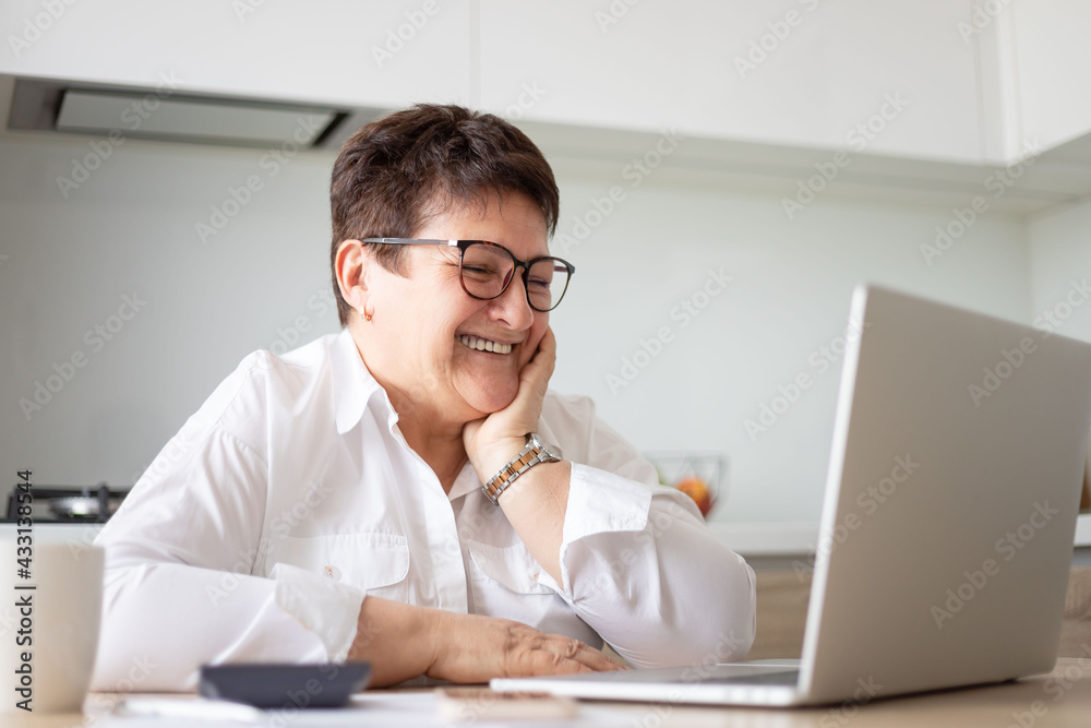 Smiling mature middle aged business woman using laptop working on computer,distance learning from home office, conference calling in virtual chat meeting. Smiling mature middle aged business woman using laptop working on computer,distance learning from home office, conference calling in virtual chat meeting.