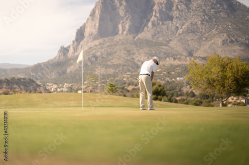 Golfer hitting ball on the green towards the hole