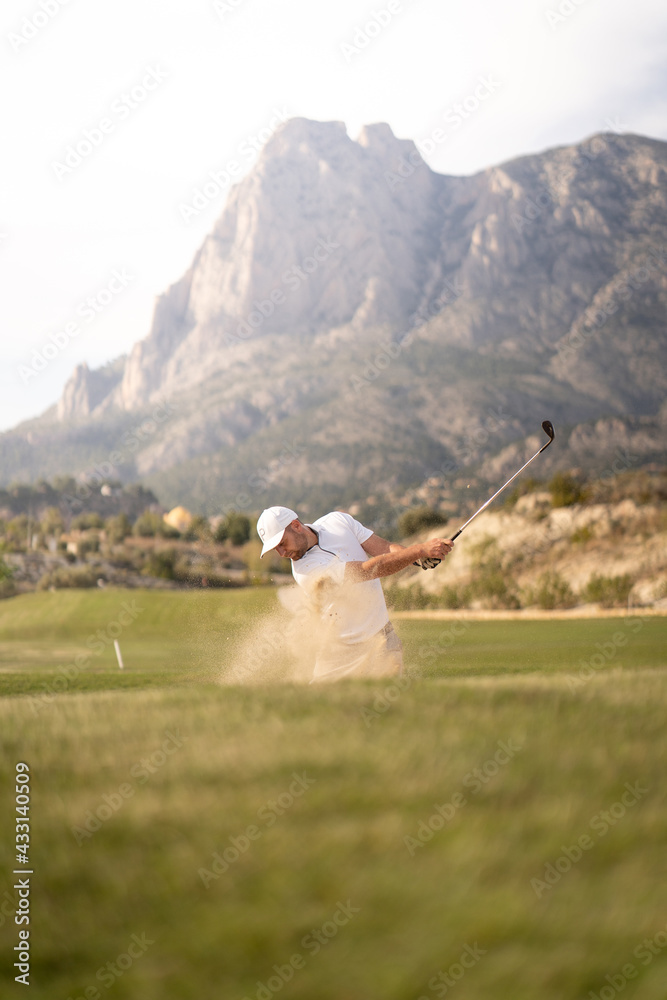 Golfer kicking the ball out of the bunker on the golf course at sunset Golfer kicking the ball out of the bunker on the golf course at sunset