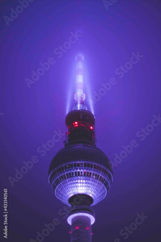 Scenic View Famous Alexanderplatz TV Tower of Berlin, Germany in Modern Futuristic Purple Light Color surrounded by Fog at Night, Close up View of Antenna
