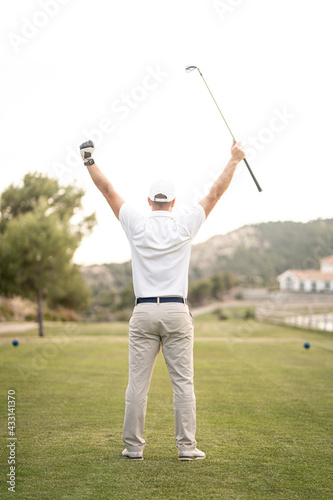 Golf player celebrating victory with his arms and his stick raised