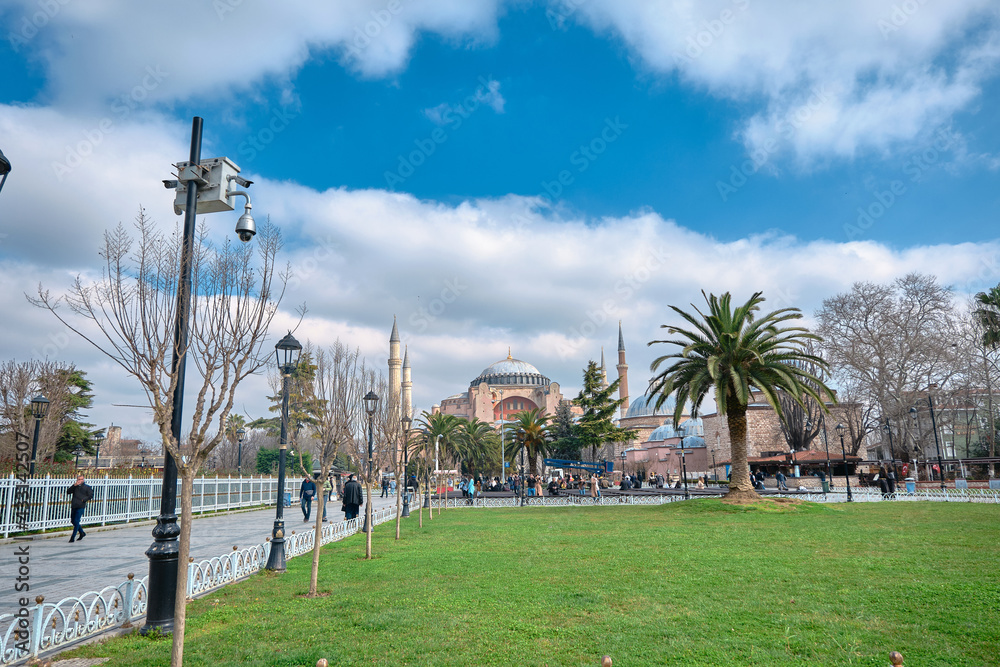 istanbul. Turkey. Ancient hagia sophia mosque by taking photo from Sultanahmet square and green grass with many people and tourist walking. Overcast and cloudscape above the hagia sophia.