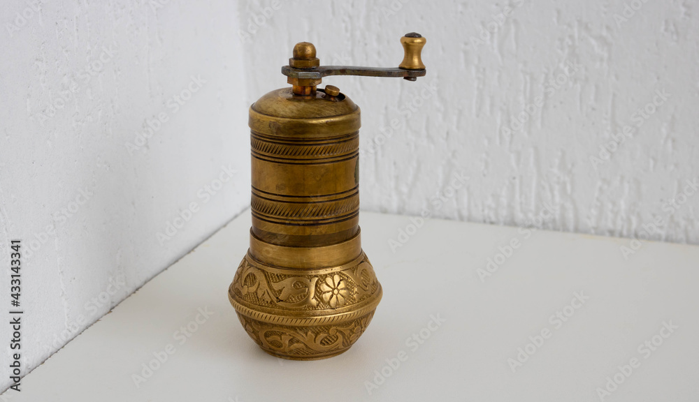Old bronze bronze coffee grinder stands on a white background Old bronze bronze coffee grinder stands on a white background