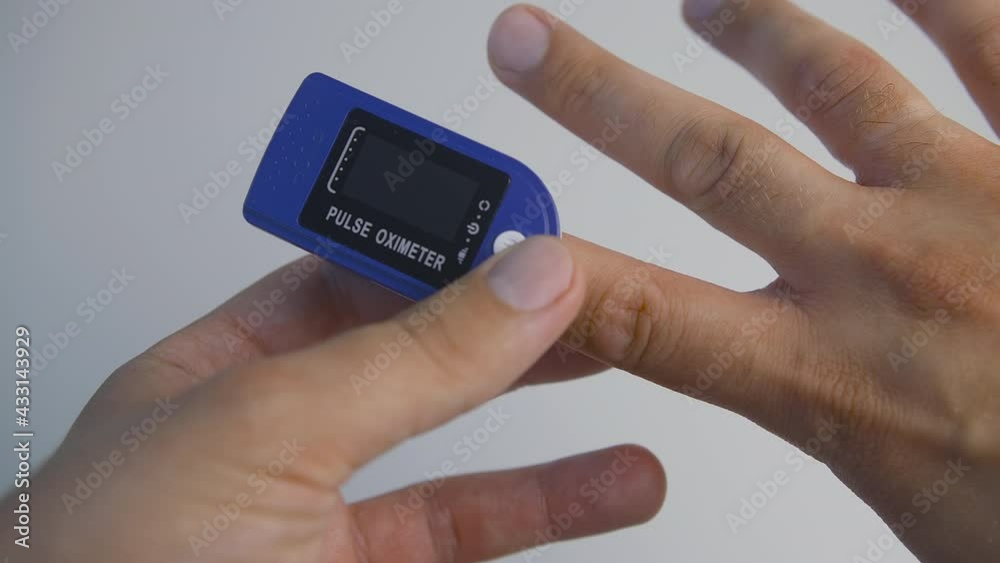 Close-up shot of man hand using pulse oximeter on the white background. Prevention of coronavirus infection Close-up shot of man hand using pulse oximeter on the white background. Prevention of coronavirus infection
