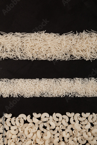 Strips of white rice and Italian pasta (vermicelli and pipe rigate) made from rice flour on dark textured background. Top view, space for text