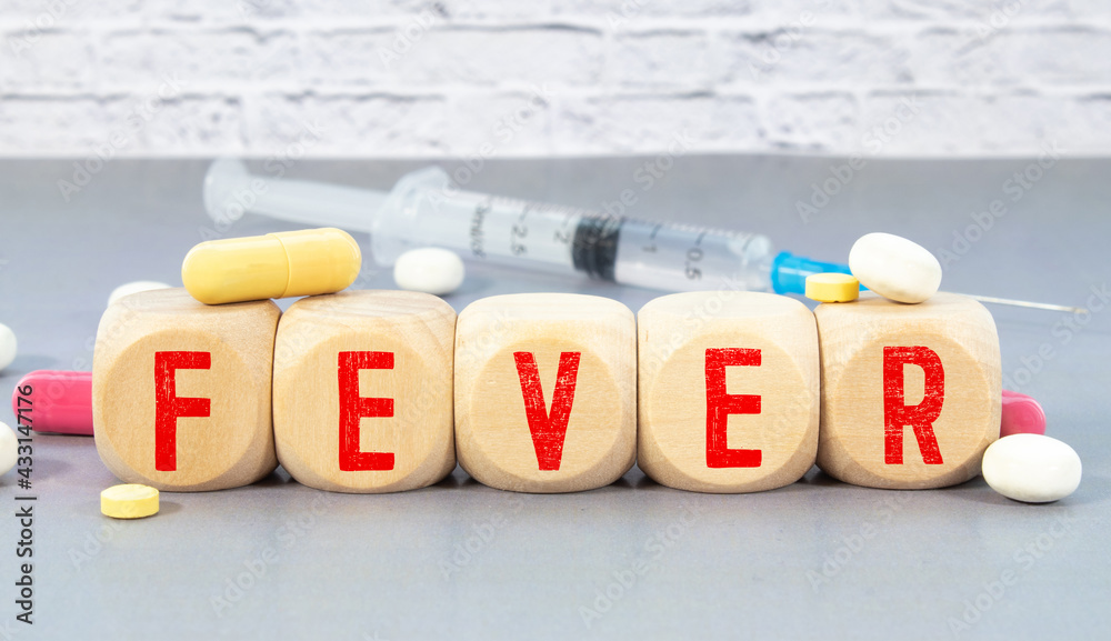 Wooden block form the word FEVER with stethoscope, pills, notepad, pen on the doctor's desktop. Wooden block form the word FEVER with stethoscope, pills, notepad, pen on the doctor's desktop.
