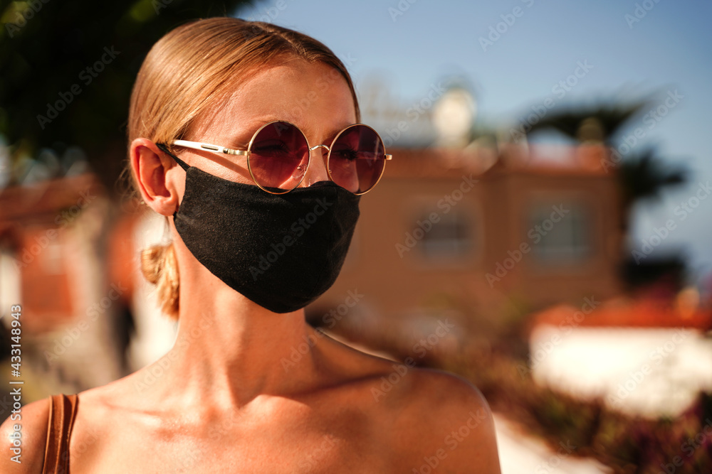 Blonde young caucasian tourist wearing medical mask during relaxing walk.
