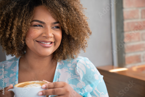Cheerful Black curly hairwoman drinking coffe