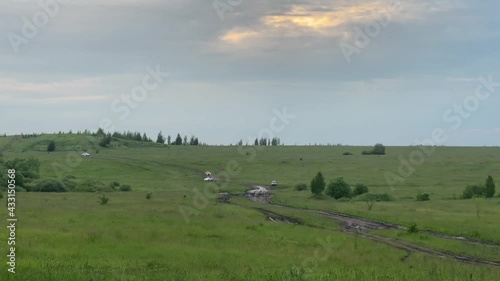 Cars go around the mud on the road in the field at sunset
