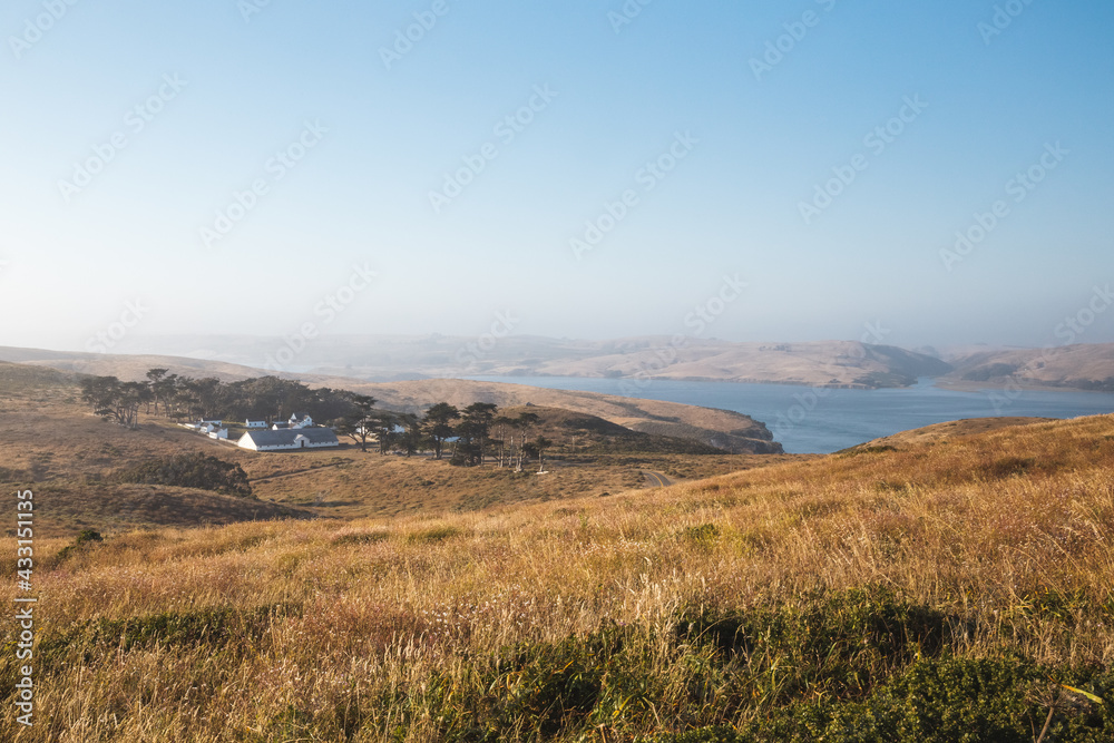 Ranch and grassy hills under a blue sky in Tomales Bay, California