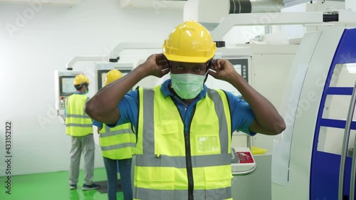 Industry production line worker with helmet and vast wearing protective face mask in front  of cutting machine. New normal working lifestyle concept after Covid-19 pandemic