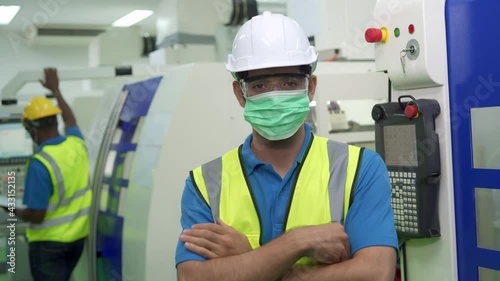 Industry production line worker with helmet and vast wearing protective face mask in front  of cutting machine. New normal working lifestyle concept after Covid-19 pandemic