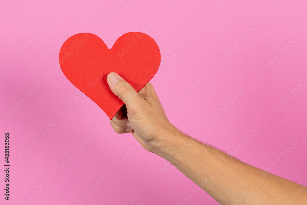 hand holding a heart on the palm with a pink background and space for text hand holding a heart on the palm with a pink background and space for text