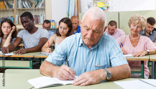 Mature man take a written exam in the classroom