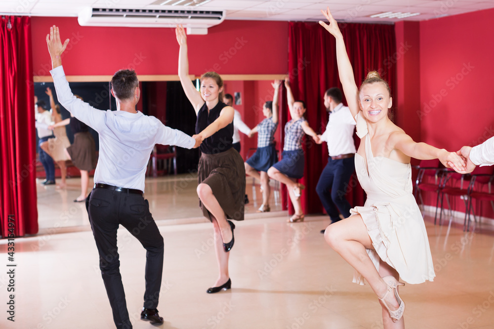 Dancing couples enjoying latin dances in modern studio