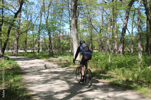 Man wearing a backpack riding a bicyle at Iroquois Woods on the Des Plaines River Trail in Park Ridge, Illinois