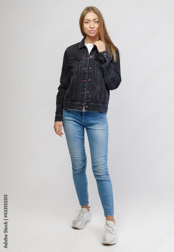 girl in a denim black jacket and blue denim pants on a white background girl in a denim black jacket and blue denim pants on a white background