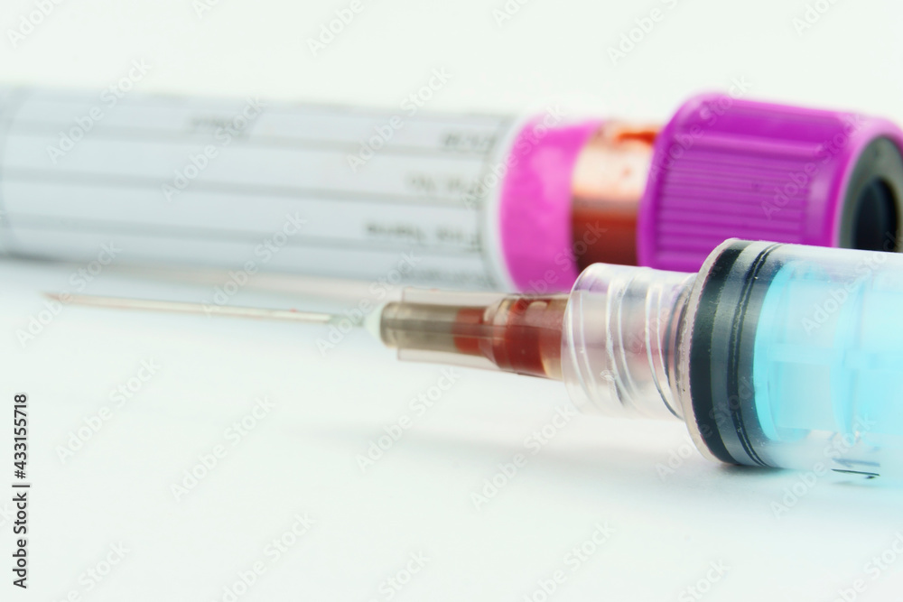 Vacuum tube for collection and blood samples on white background..Transparent with purple cap and a syringe. Label to identify the data. Selective focus. Macro. Vacuum tube for collection and blood samples on white background..Transparent with purple cap and a syringe. Label to identify the data. Selective focus. Macro.