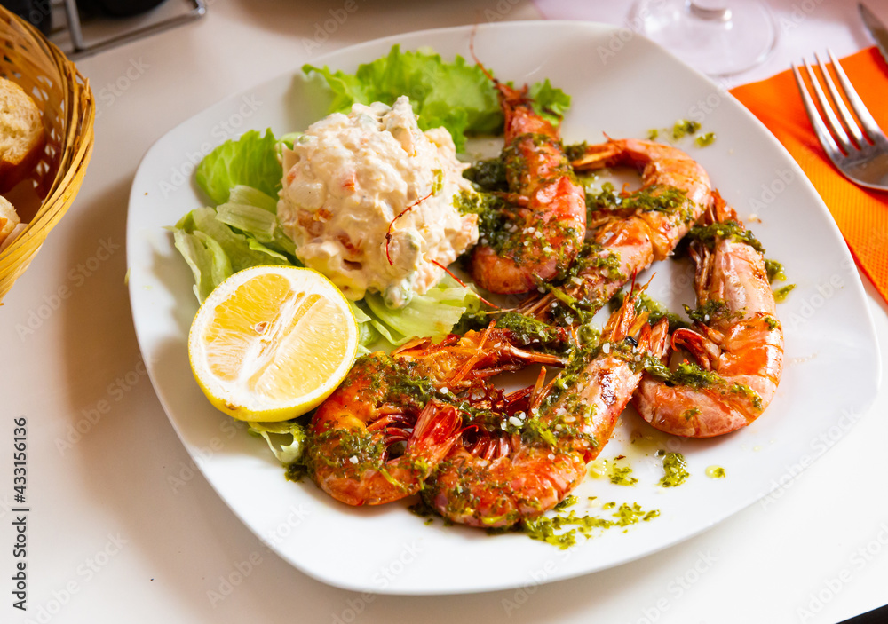 Image of delicious king shrimps and salad from potatoes at plate