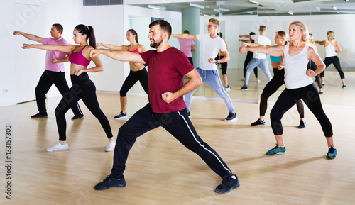 Cheerful men women performing modern dance in fitness studio