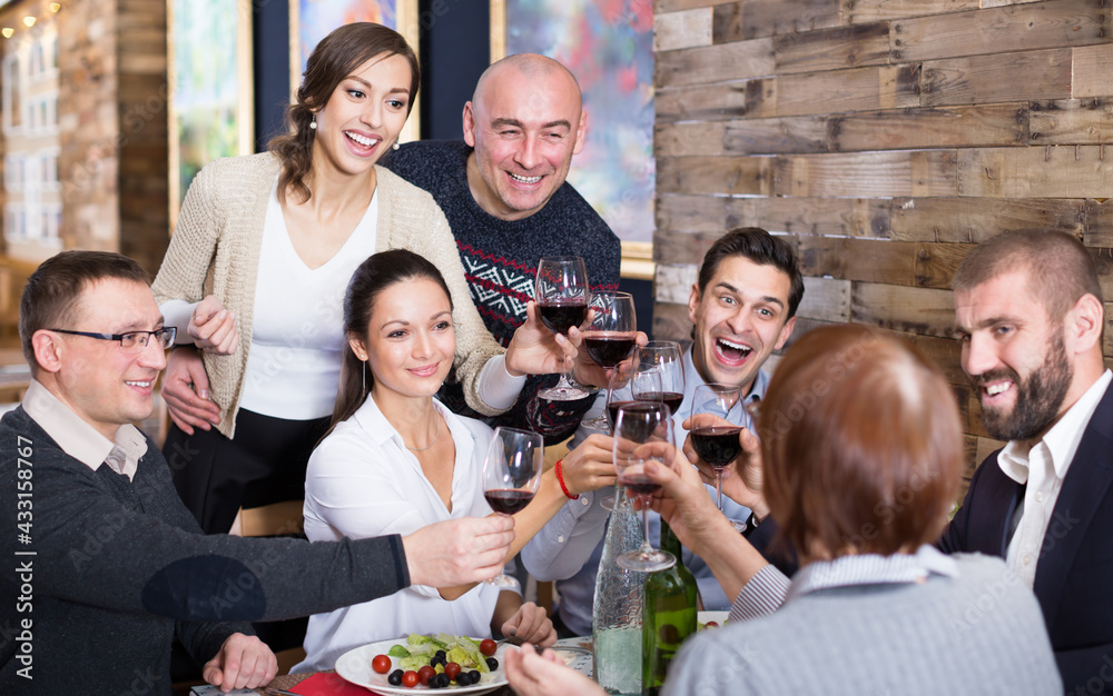 Portrait of happy company men and women in restaurant with the glass wine