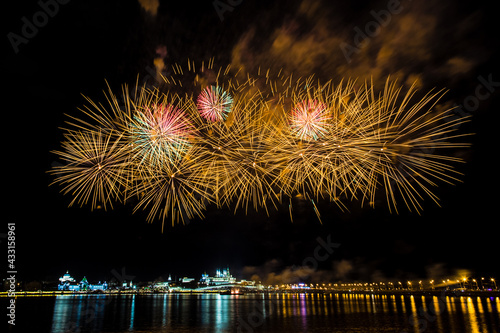 bright festive fireworks with beautiful flowers bloom over the river on a warm clear evening