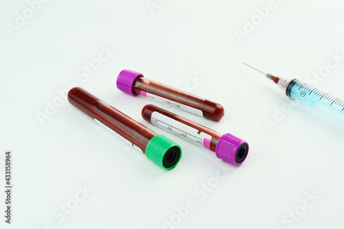 Vacuum tubes for collection and blood samples on white background..Transparent with purple and green cap and a syringe. Label to identify the data. Selective focus.